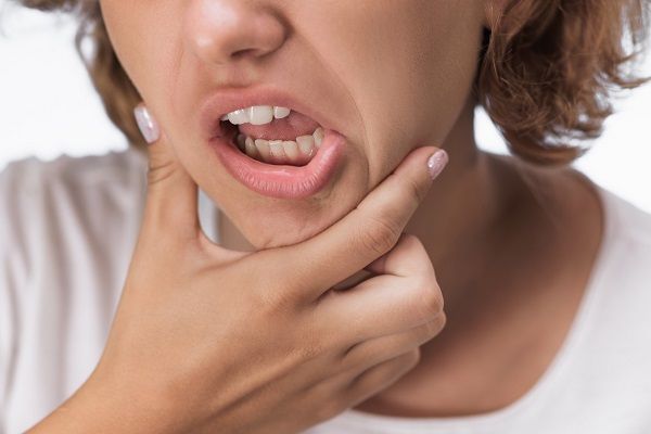 woman clutching jaw in need of chiropractic care for TMJ