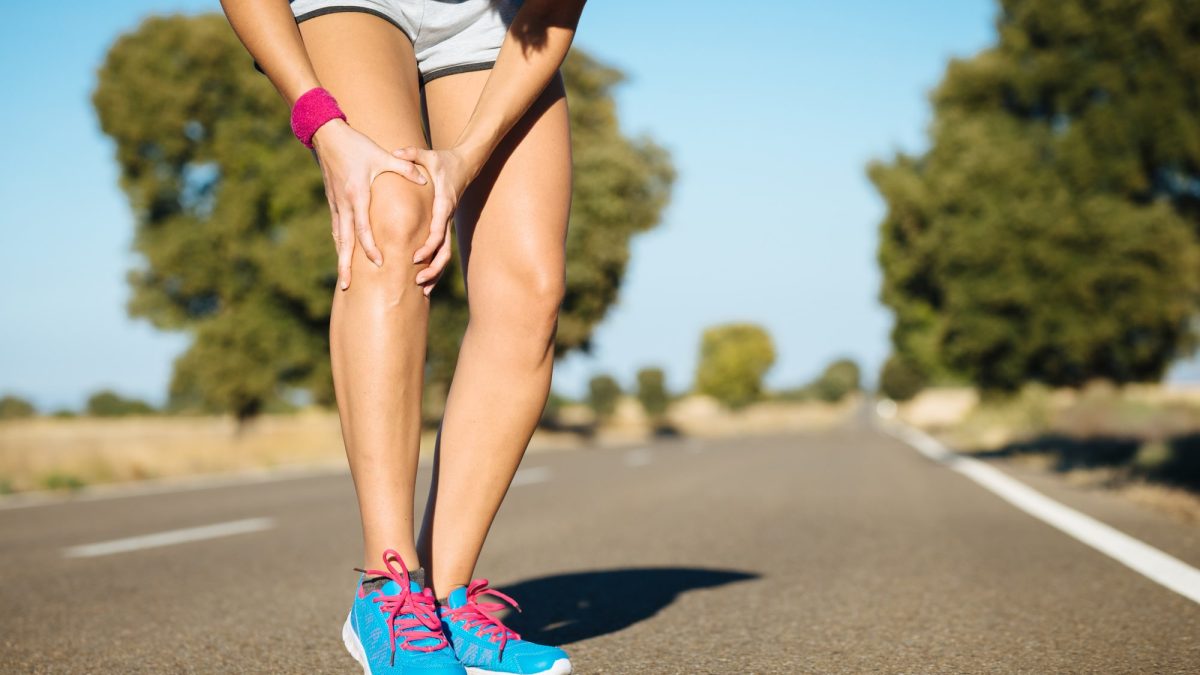 Runner holding shin in pain during training in Brisbane